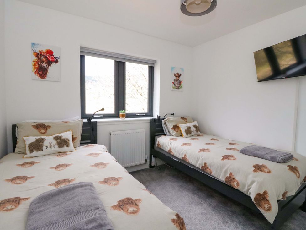 A bedroom with two single beds and a window at 25 Strathtay Lodges Aberfeldy