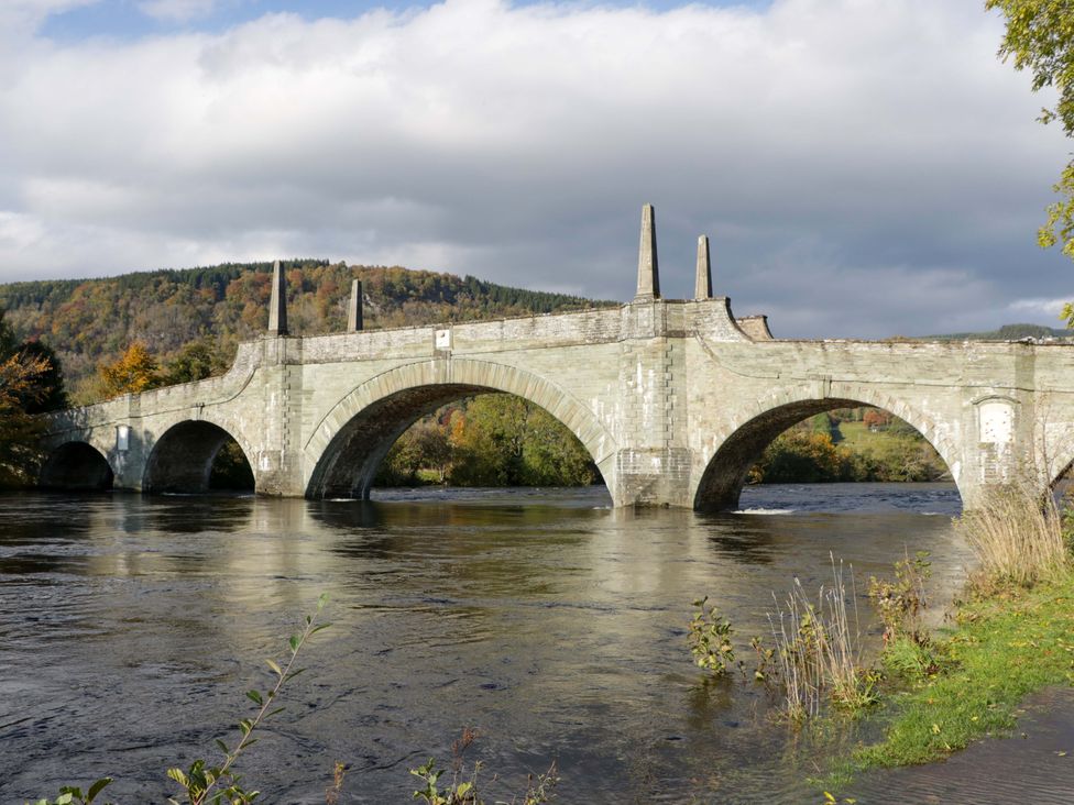 A stone bridge over a river with trees in the background at 25 Strathtay Lodges Aberfeldy