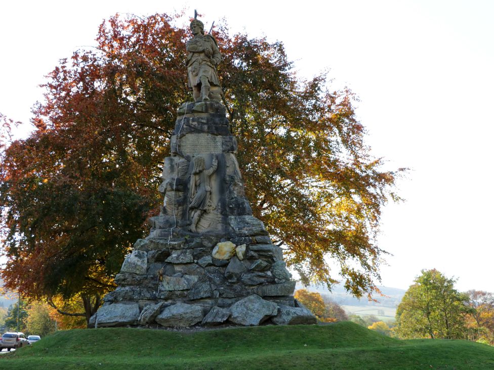 A monument with a statue and plaque surrounded by trees at 25 Strathtay Lodges Aberfeldy