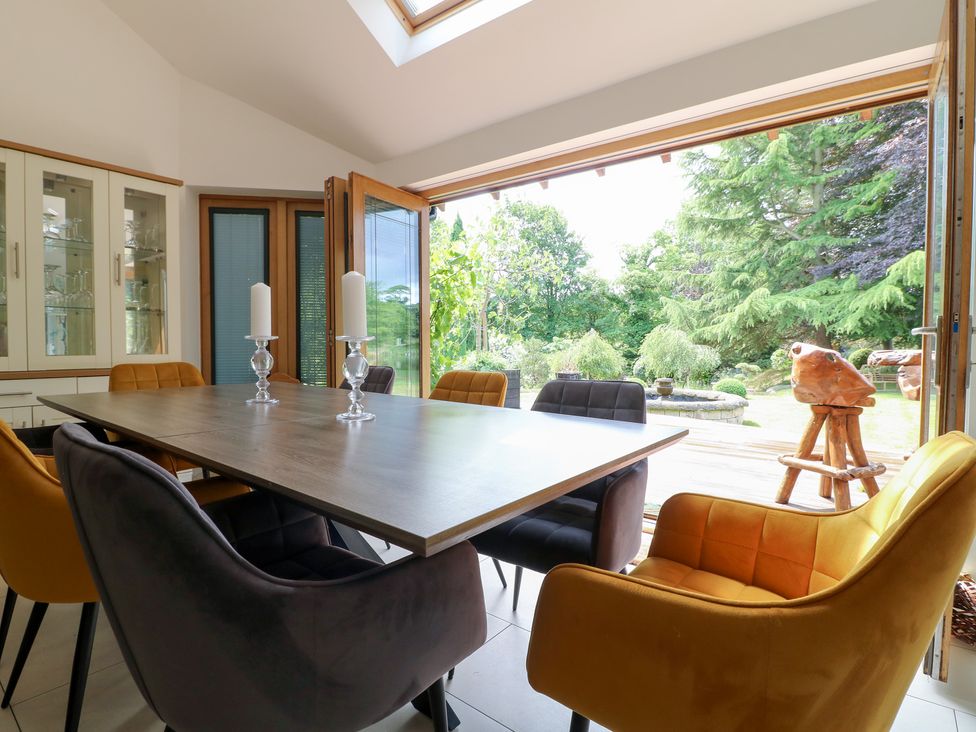 A dining room with a table and chairs overlooking a garden at Old Mill House in Cuckney