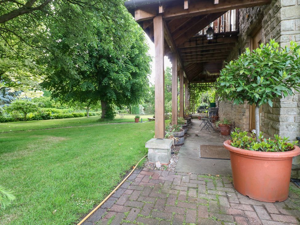 A garden view with trees and a patio area at Old Mill House Cuckney