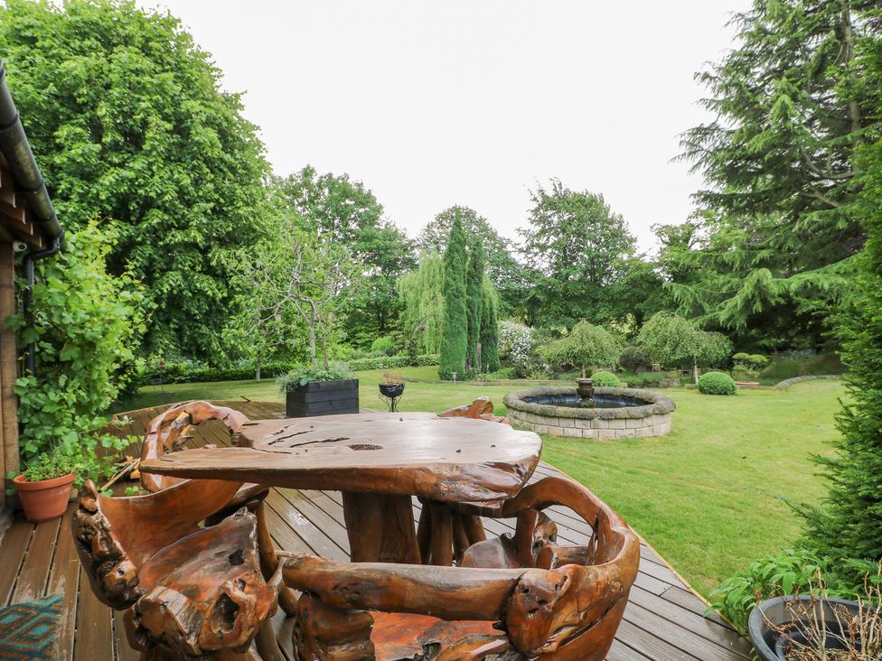 A garden with a wooden table and chairs near a fountain at Old Mill House Cuckney
