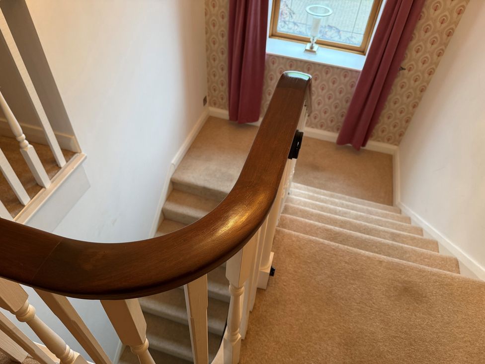 A staircase with a wooden railing and a window at Old Mill House in Cuckney