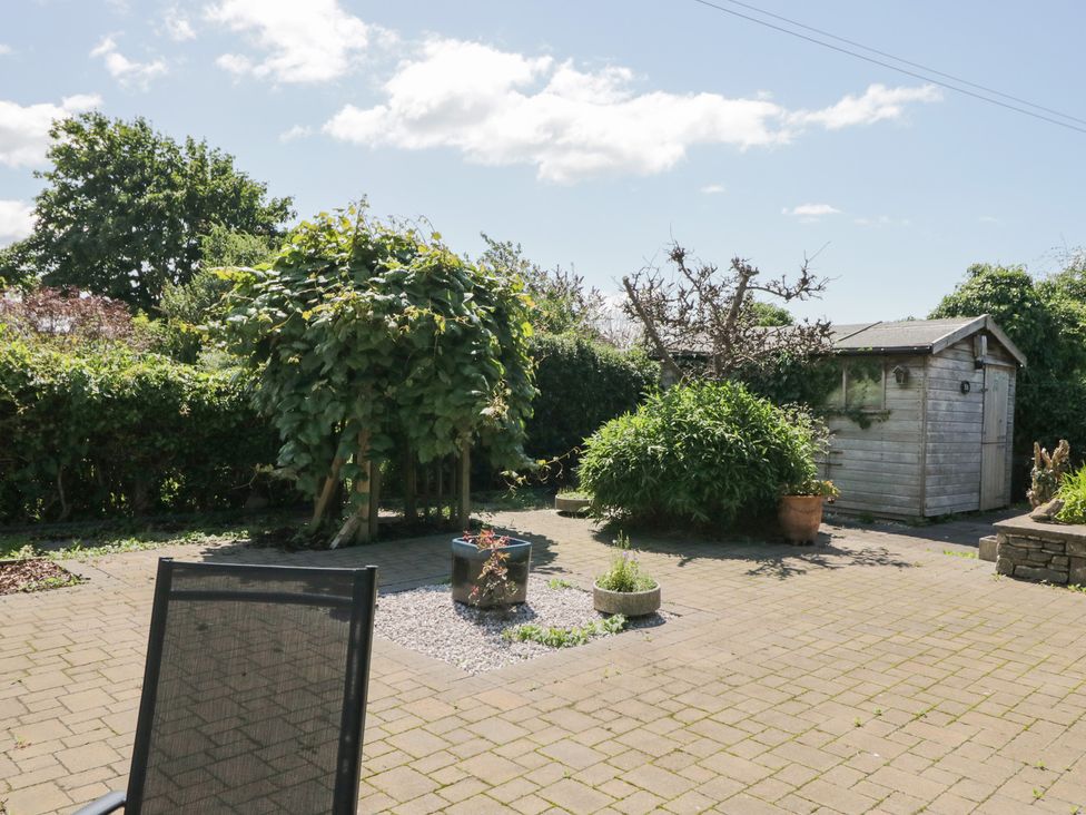 A garden with a shed, planter, and gravel area at Timekeeper's Cottage in Warton near Carnforth