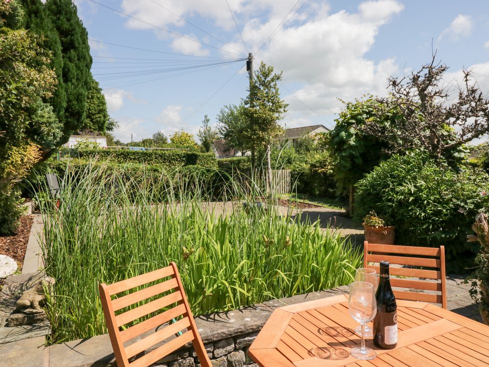 A garden with a table and wine bottle at Timekeeper's Cottage in Warton near Carnforth