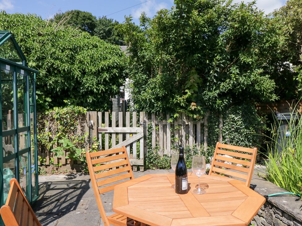 A table with chairs and a bottle in the garden at Timekeeper's Cottage Warton near Carnforth