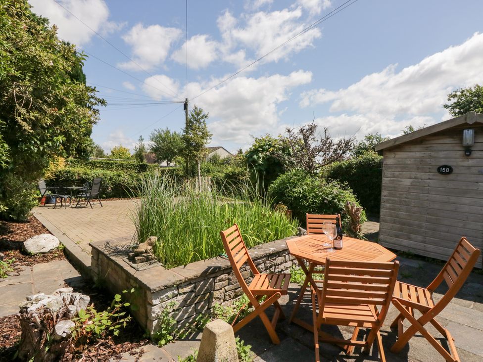 A garden with a wooden table and chairs at Timekeeper's Cottage in Warton near Carnforth