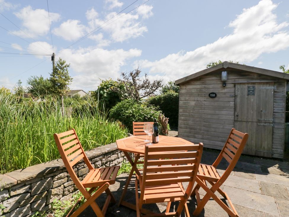 A garden with a wooden table and chairs at Timekeeper's Cottage in Warton near Carnforth