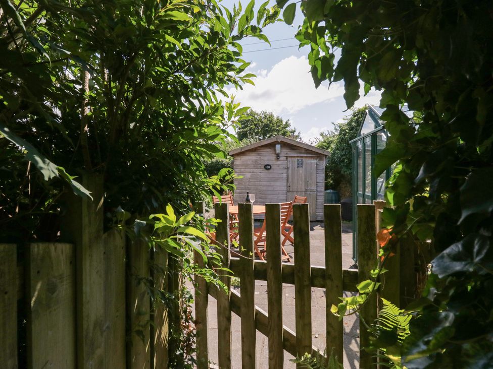A garden with a wooden shed and seating area at Timekeeper's Cottage Warton near Carnforth