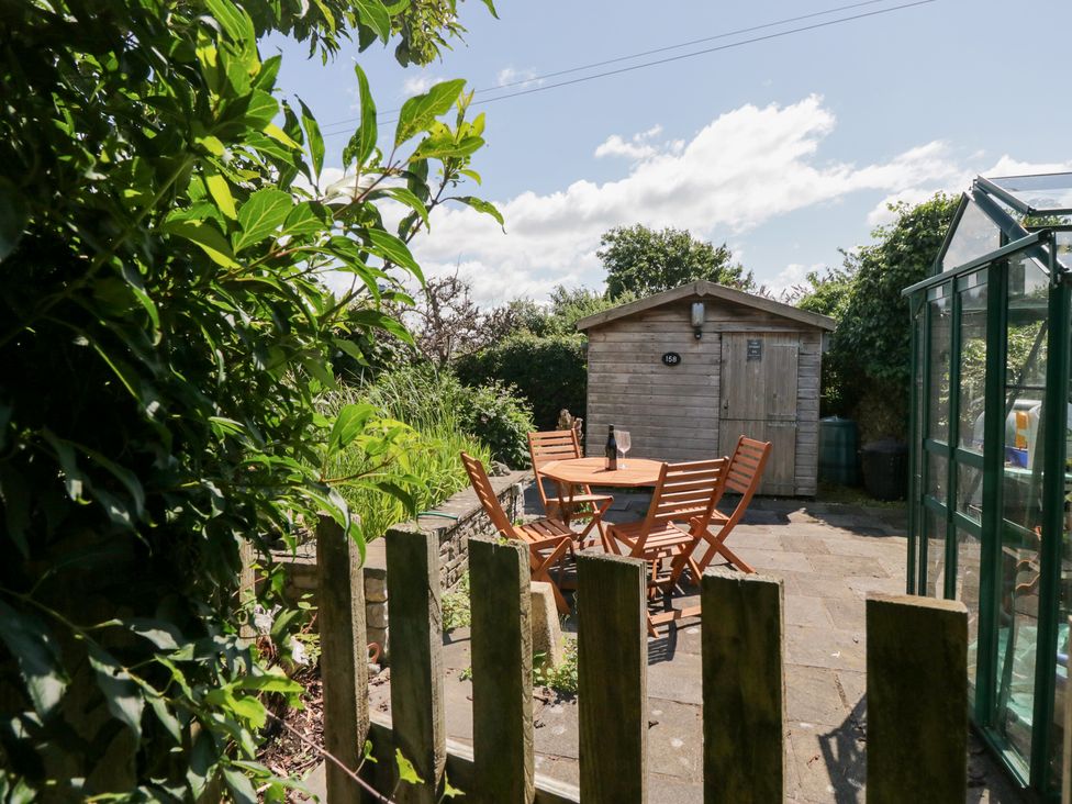 A garden with a wooden shed and dining furniture at Timekeeper's Cottage Warton near Carnforth