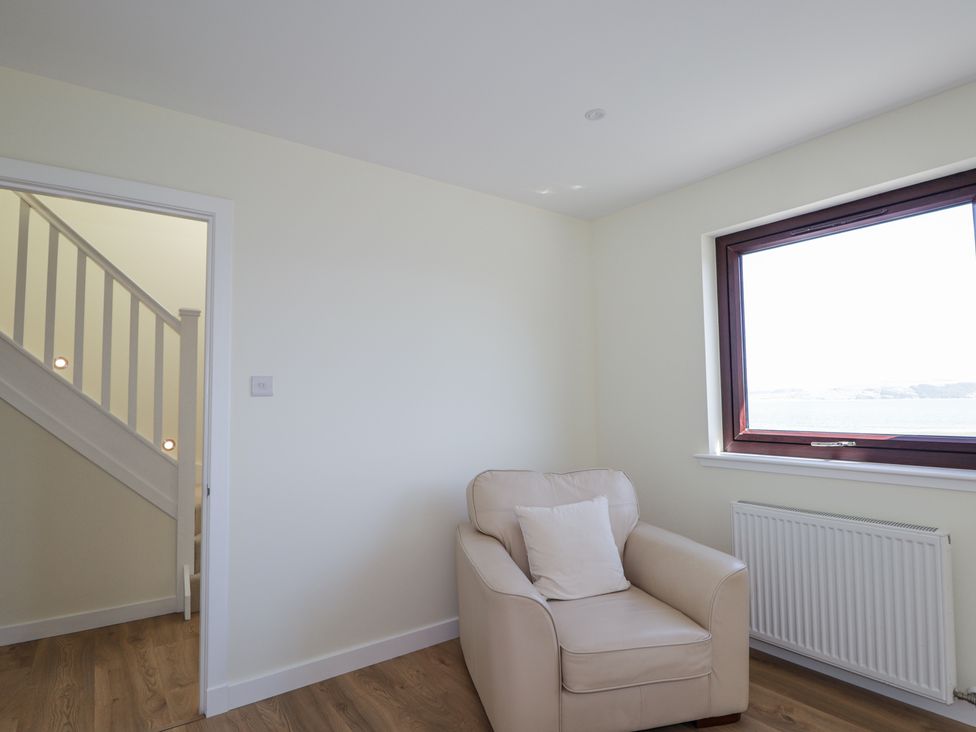 A room with an armchair and a window showing a view at Calmdale in Inverasdale near Poolewe