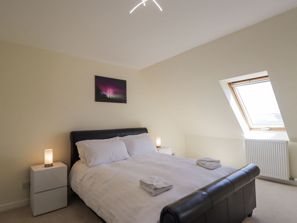 A bedroom with a double bed two bedside tables with lamps and a skylight window at Calmdale in Inverasdale near Poolewe