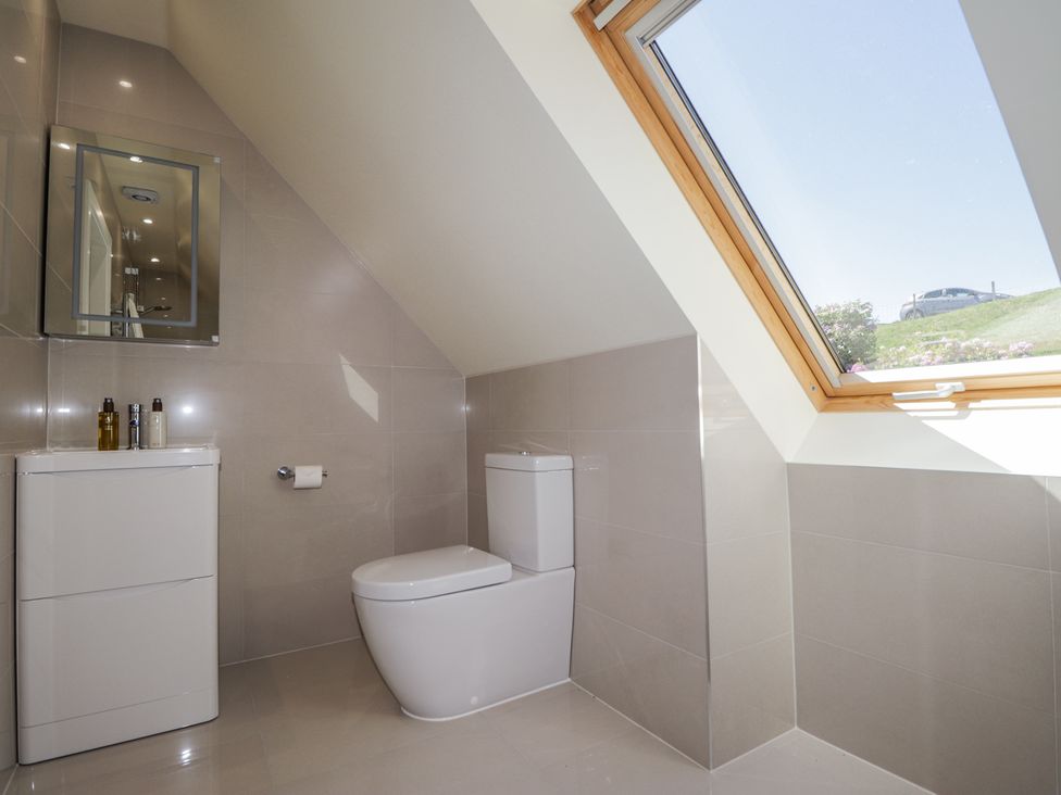 A bathroom with a toilet sink mirror and large skylight window at Calmdale in Inverasdale near Poolewe