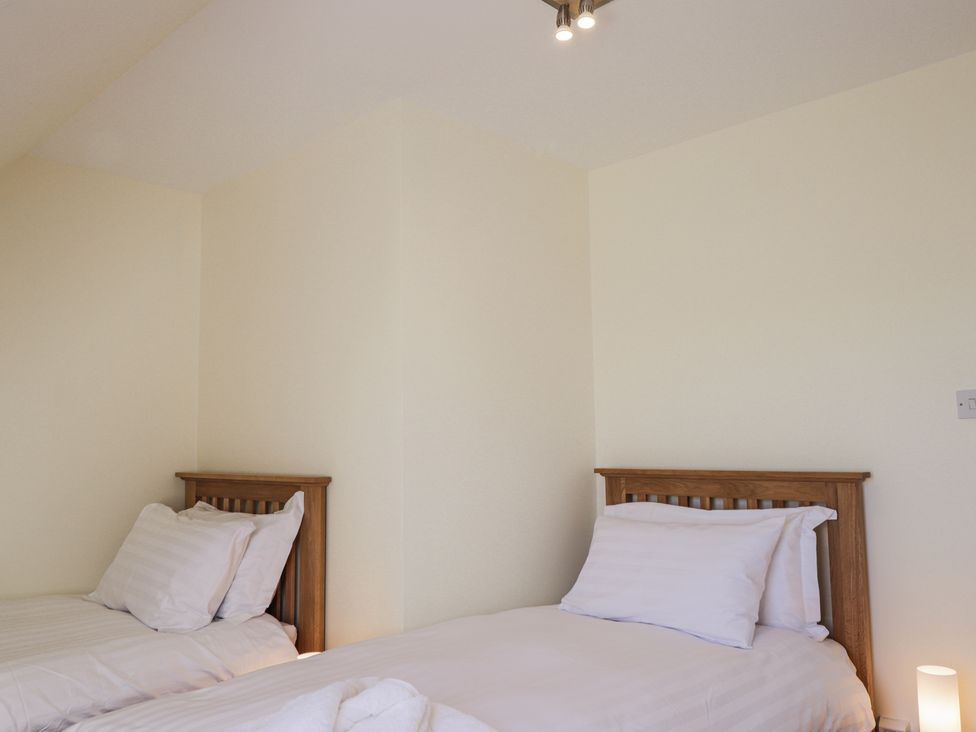 A bedroom with two single beds with white bedding and wooden headboards at Calmdale in Inverasdale near Poolewe