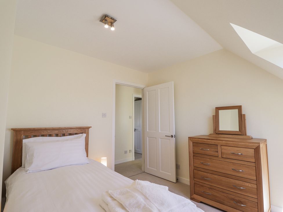 A bedroom with a single bed a wooden dresser with a mirror and an open door at Calmdale Inverasdale near Poolewe