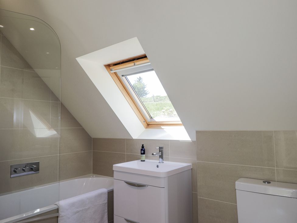 A bathroom with a bathtub towel sink with faucet and a skylight window at Calmdale in Inverasdale near Poolewe