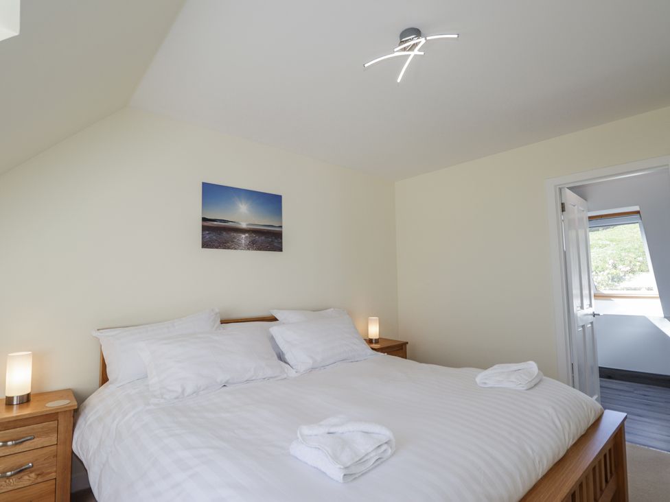 A bedroom with a double bed white linens bedside tables with lamps and a picture on the wall at Calmdale in Inverasdale near Poolewe