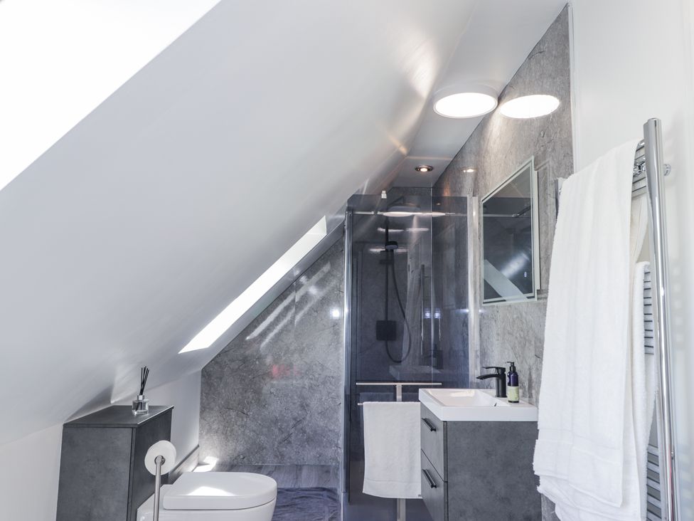 A bathroom with a toilet a shower a sink a mirror and towels at Calmdale Inverasdale near Poolewe