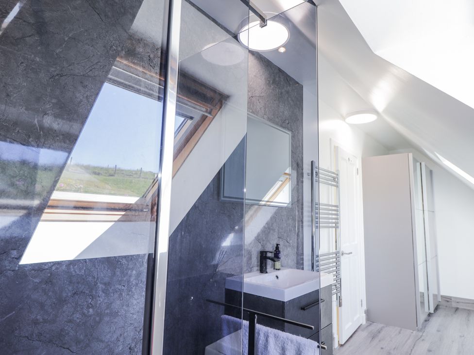 A bathroom with a sink cabinet and mirror skylight window and towel rack at Calmdale in Inverasdale near Poolewe