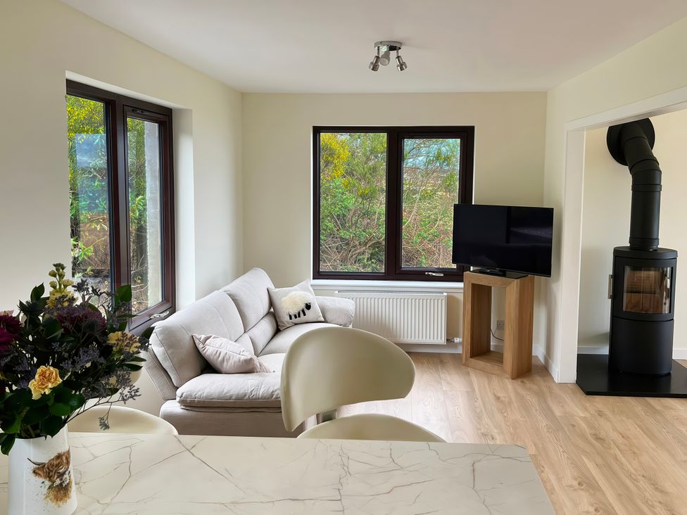 A living room with a sofa and a television at Calmdale in Inverasdale near Poolewe