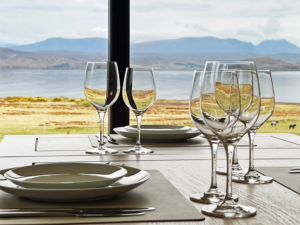 A dining room table set with wine glasses and plates at Calmdale in Inverasdale near Poolewe