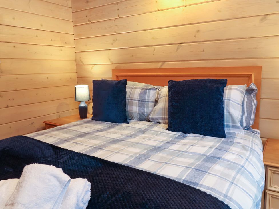 A bedroom with a bed and bedside lamp at Elderberrys Lodge in Bideford