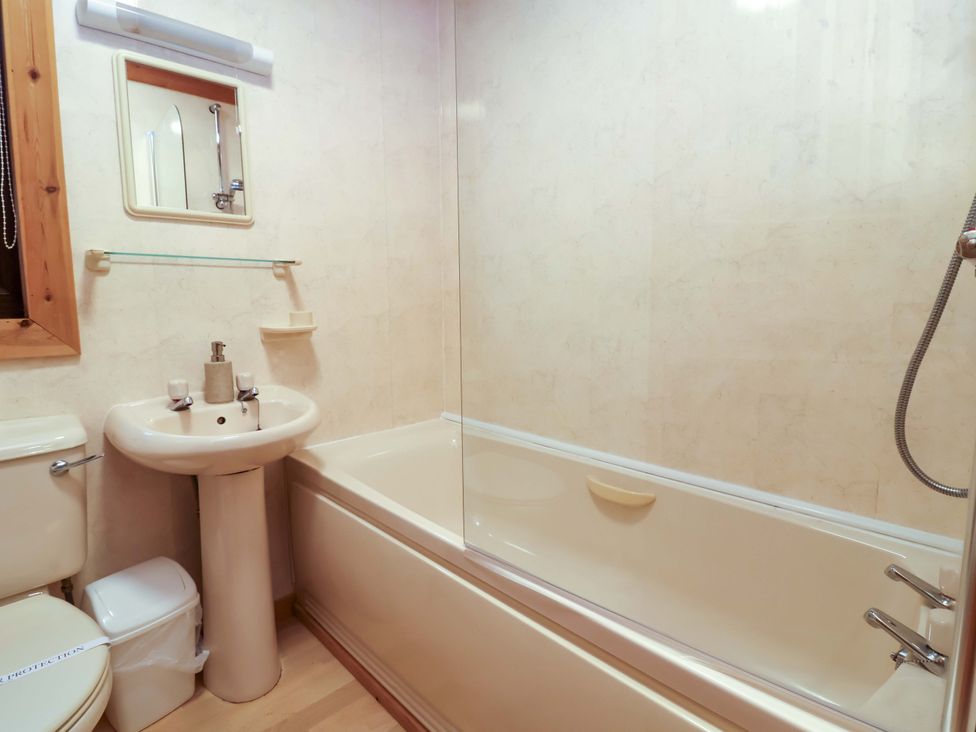 A bathroom with sink, toilet, bath and mirror at Elderberrys Lodge in Bideford