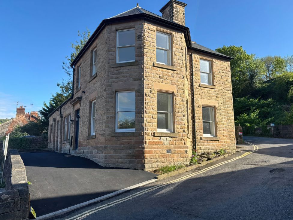 A building with multiple windows and a driveway at Holt Hall - Ground Floor Apartment in Matlock