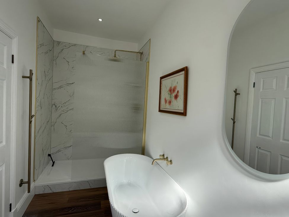 A bathroom with a bathtub and shower at Holt Hall - Ground Floor Apartment in Matlock