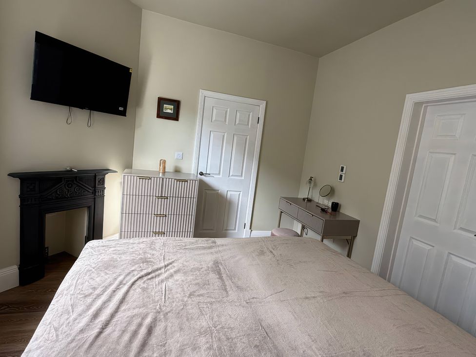 A bedroom with a bed, television, and desk at Holt Hall - Ground Floor Apartment in Matlock