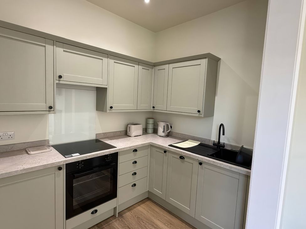 A kitchen with appliances and cabinets at Holt Hall - Ground Floor Apartment in Matlock