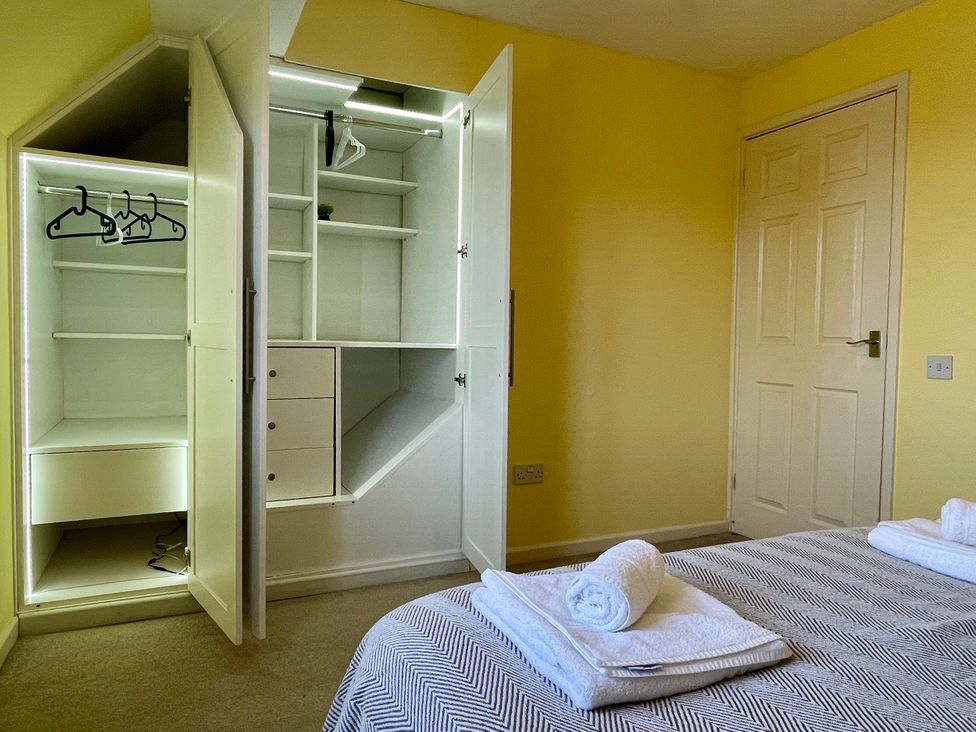 A bedroom with a wardrobe and towels on the bed at 20 Honeycroft in Bourton-On-The-Water