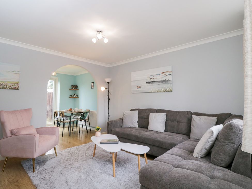A living room with a grey sofa, armchair, and dining area at 20 Honeycroft Bourton-On-The-Water