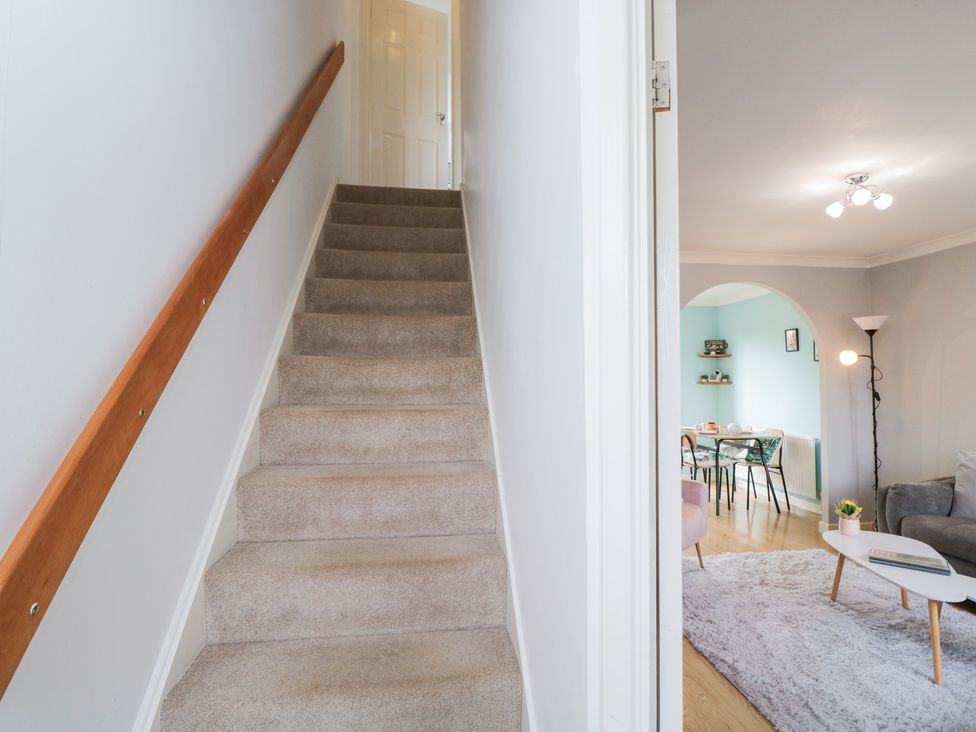 A staircase leading to an upper floor with a view of a living area at 20 Honeycroft Bourton-On-The-Water