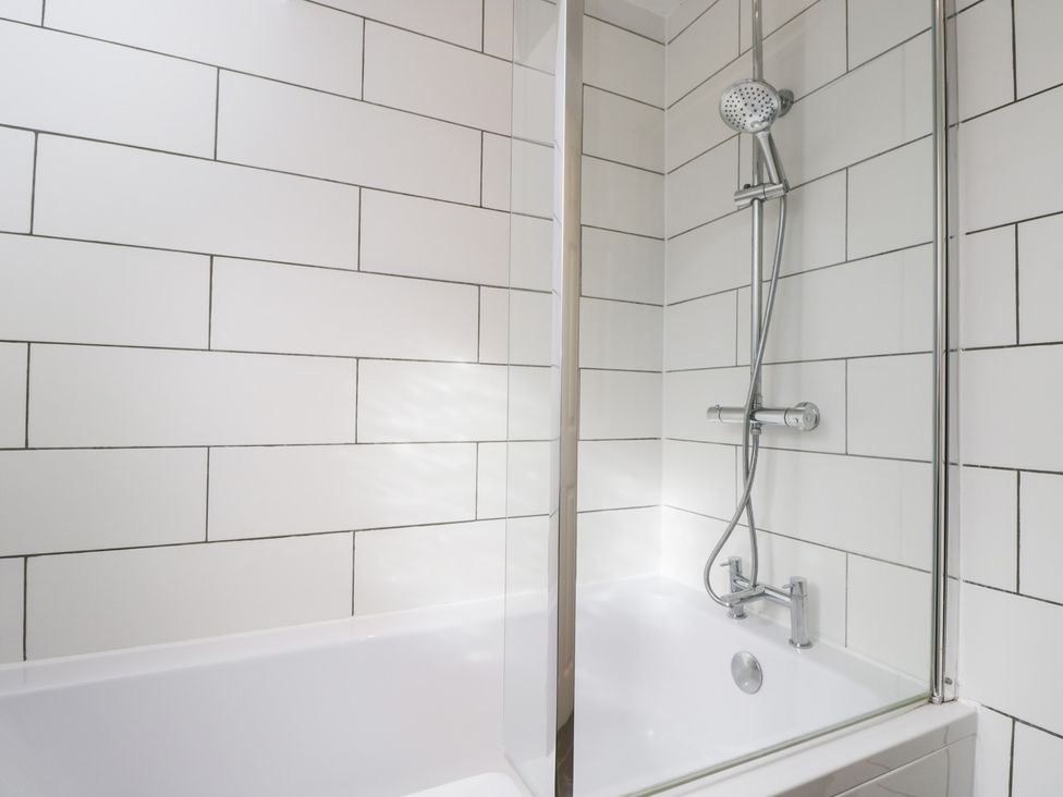 A bathroom with a bathtub and shower setup at 20 Honeycroft in Bourton-On-The-Water