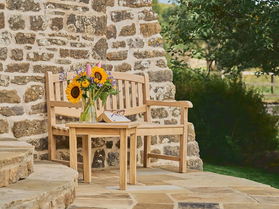 A bench and table with flowers on it at The Reading Rooms in Oughtershaw near Buckden