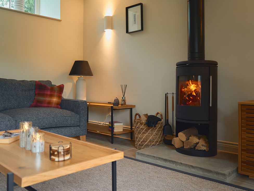 A living room with a wood stove and sofa at The Reading Rooms in Oughtershaw near Buckden