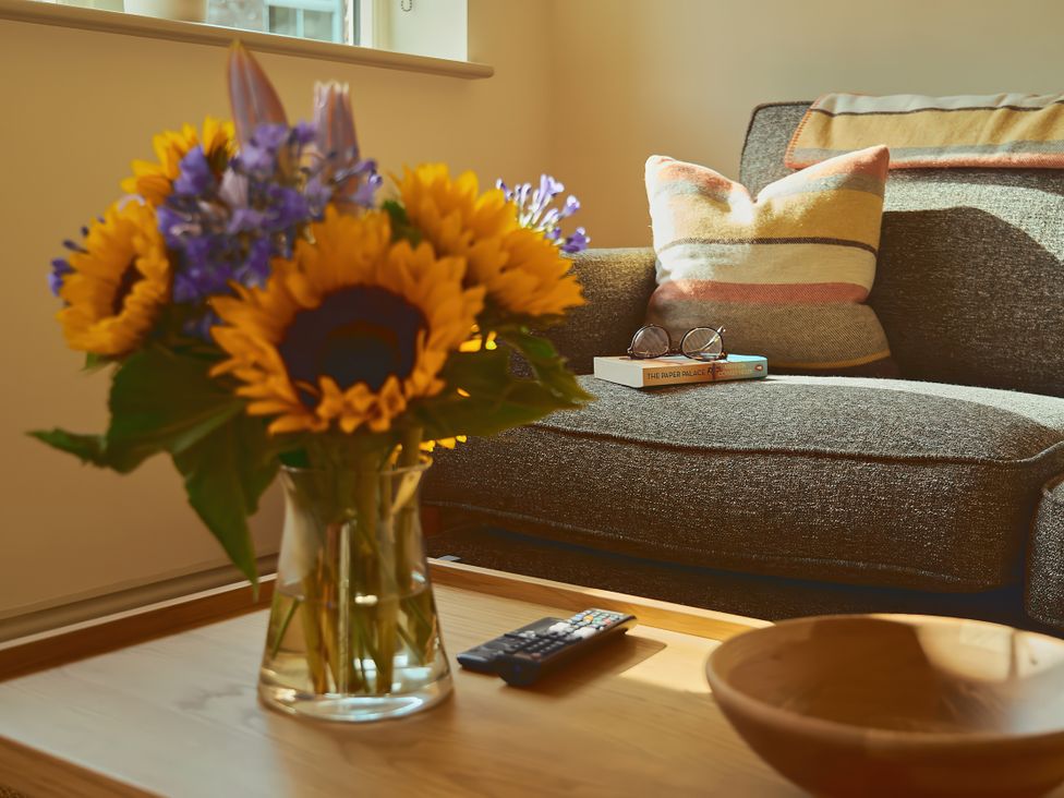 A living room with a sofa and flowers on a table at The Reading Rooms in Oughtershaw near Buckden