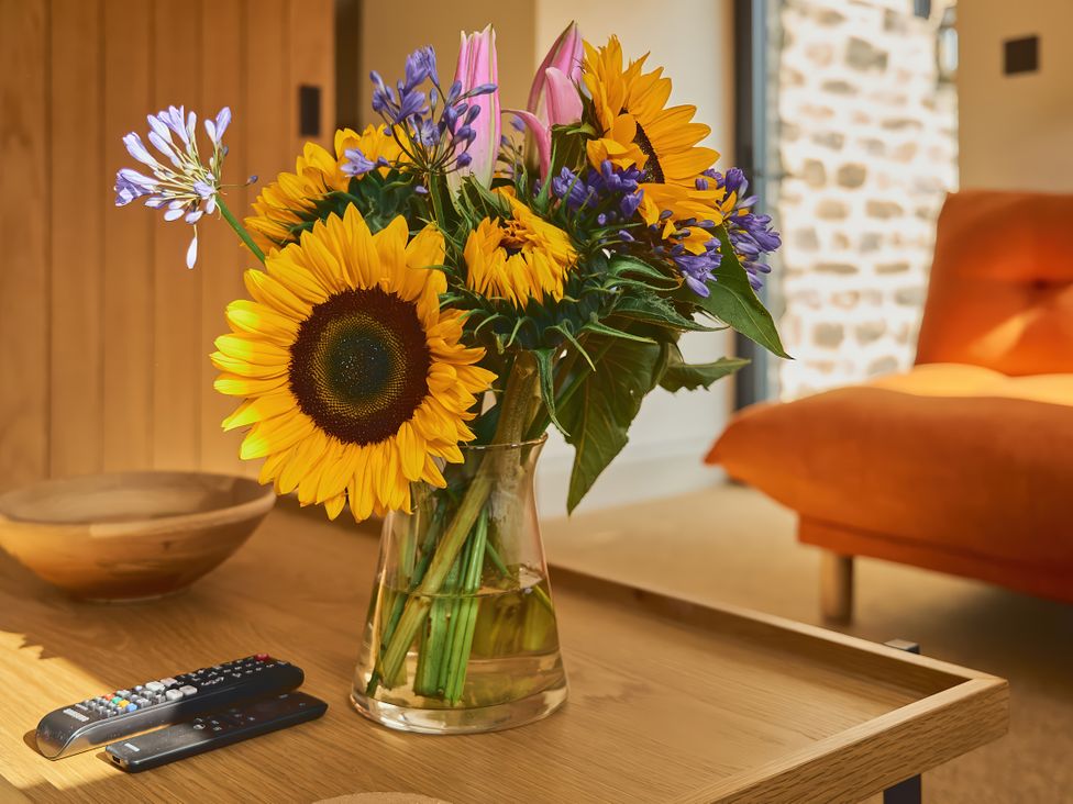A table with flowers and remote controls at The Reading Rooms in Oughtershaw near Buckden