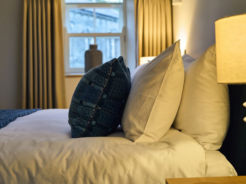 A bedroom with pillows on a bed and a lamp at The Reading Rooms in Oughtershaw near Buckden