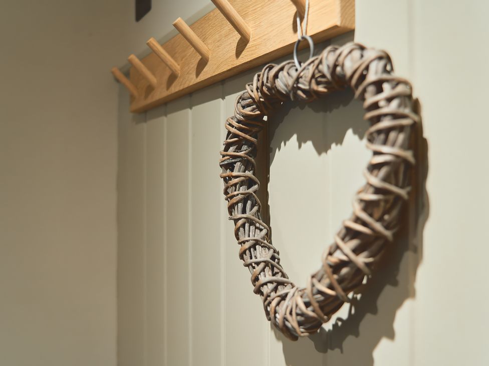 A woven heart hanging on a wall near a coat rack at The Reading Rooms Oughtershaw near Buckden