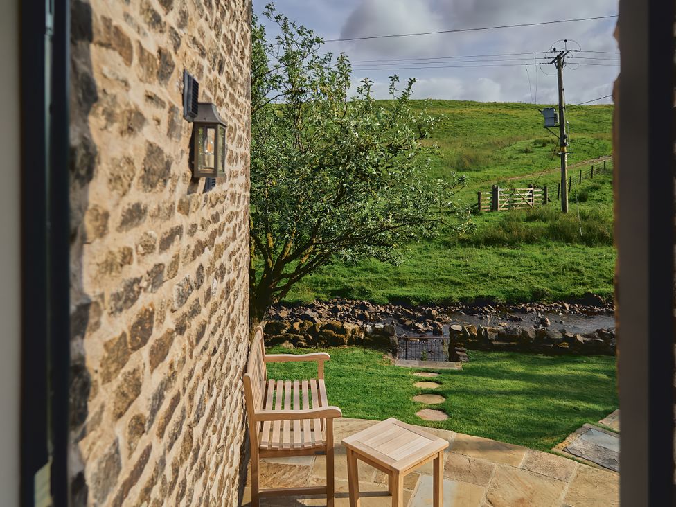 An outdoor seating area with a bench and small table at The Reading Rooms in Oughtershaw near Buckden