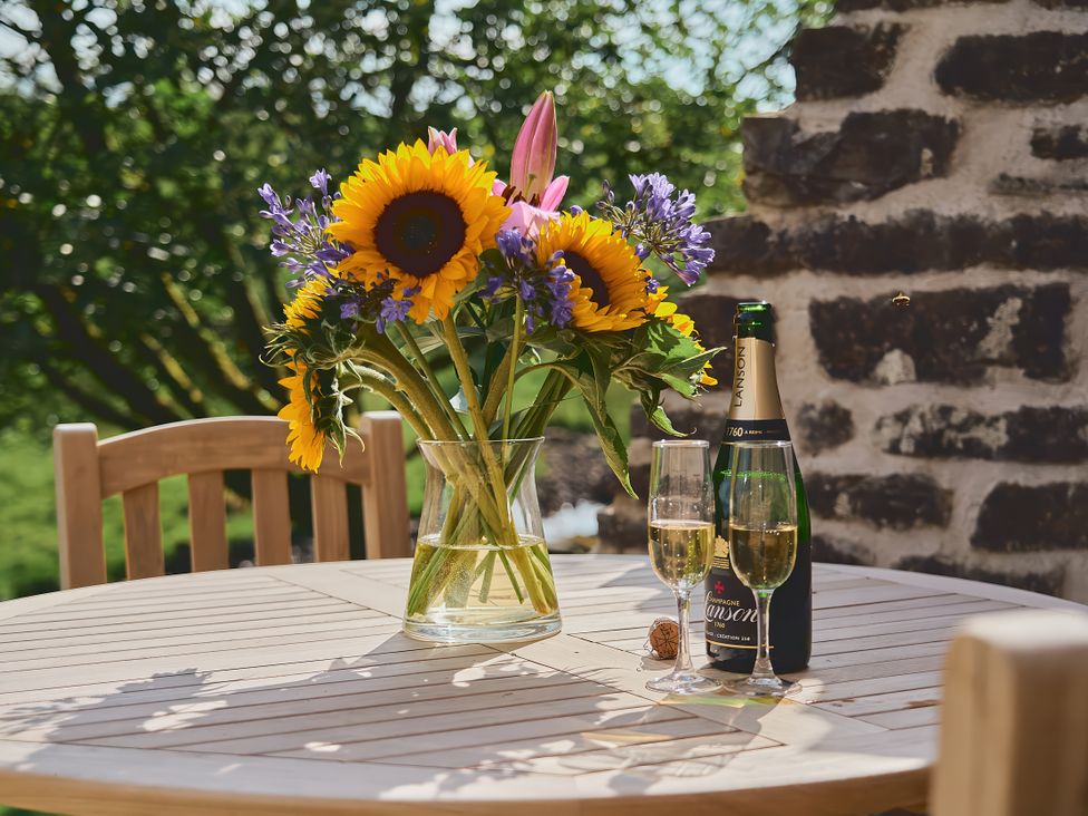 A table with flowers in a vase and champagne glasses at The Reading Rooms Oughtershaw near Buckden