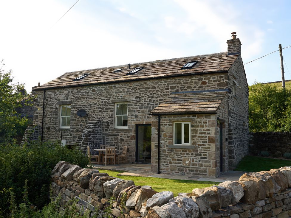 A stone house with a patio furniture setup at The Reading Rooms Oughtershaw near Buckden