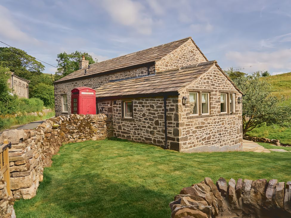 A cottage with a red phone box and stone wall at The Reading Rooms in Oughtershaw near Buckden