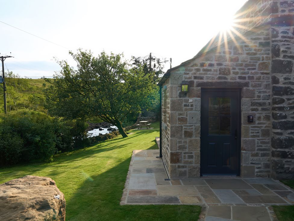 A garden with a stone building and a pathway at The Reading Rooms Oughtershaw near Buckden