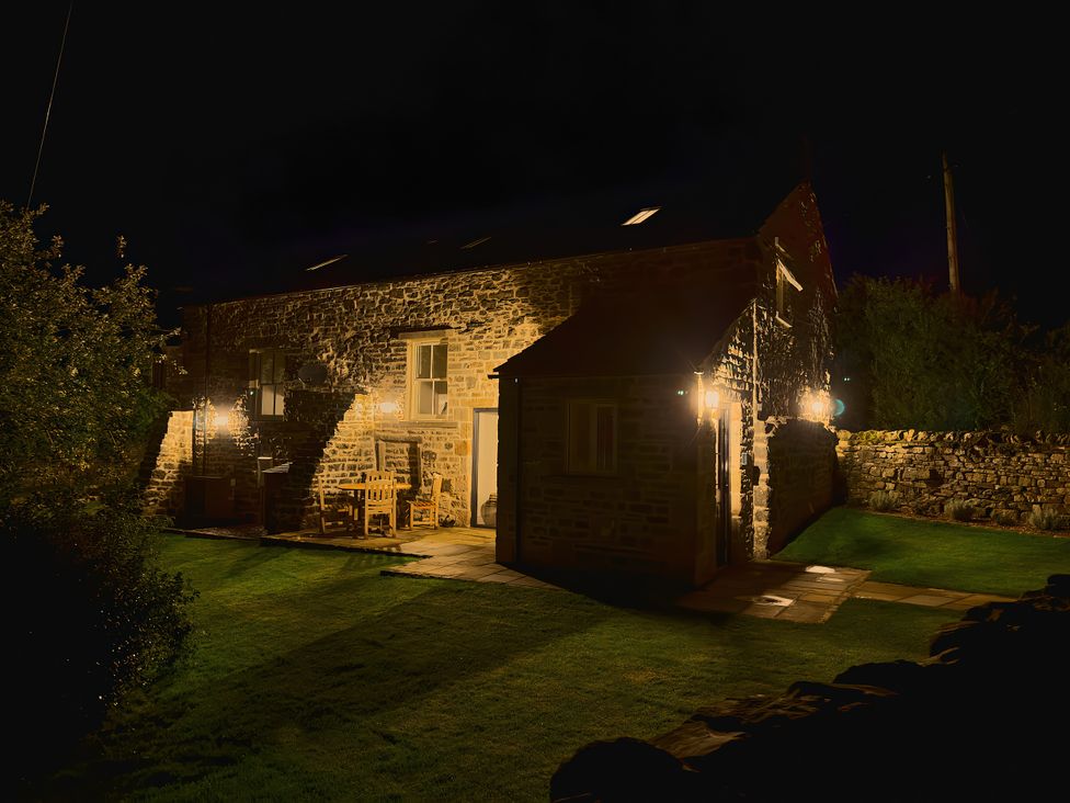 A building at night with illuminated garden features at The Reading Rooms in Oughtershaw near Buckden