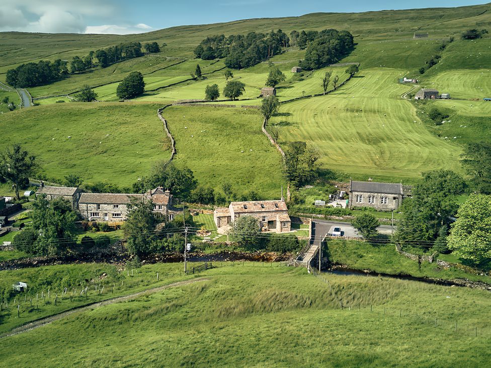 An aerial view of houses and fields at The Reading Rooms Oughtershaw near Buckden