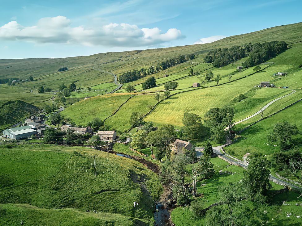 An aerial view of fields and buildings in a rural area at The Reading Rooms Oughtershaw near Buckden