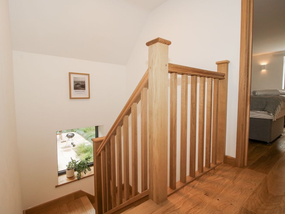 A staircase with wooden handrail and window at The Barn in Acton near Bishop's Castle
